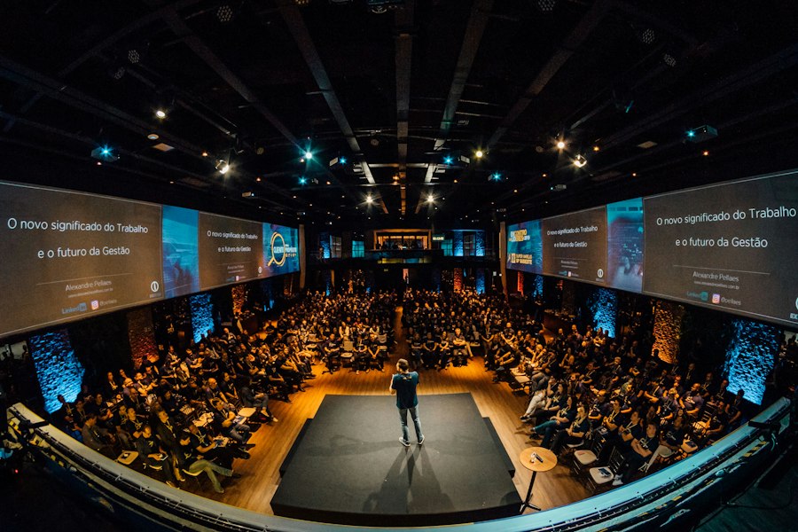 A speaker on stage in front of a large conference audience